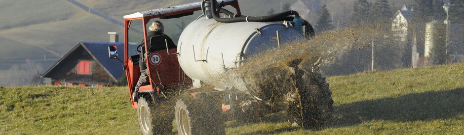 Berggülle Auf einer Bergeweide. Im Vordergrund fährt ein Bauer mit dem Transportfass und bringt die Gülle aus